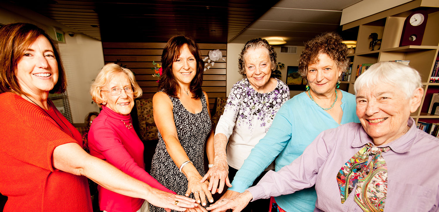 group of seniors and caregivers with "hands in"